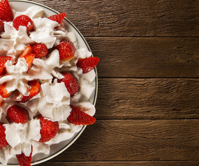 Strawberry with chantilly cream in a dish on a wooden table