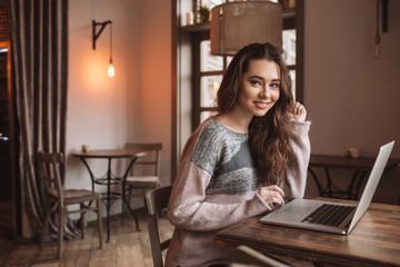 Sticker - Cheerful young woman in cafe using a laptop