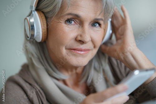 Foto Ältere Frau zu Hause, die Musik mit Smartphone hört