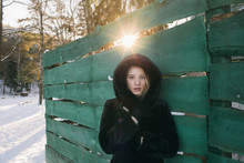 Portrait Of Young Woman Standing Against Green Wooden Fence