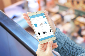 Poster - Woman showing online shop app on mobile phone. Shopping center in background.