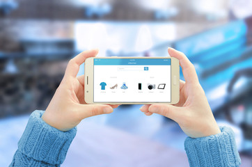 Poster - Phone in horizontal position in woman hands. Commerce app with modern user friendly interface on mobile display. Business center in background.