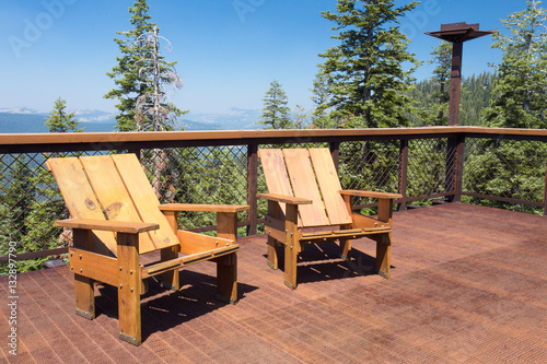 Fotografie, Obraz Two wood chairs on outdoor sunny deck with mountains in the background