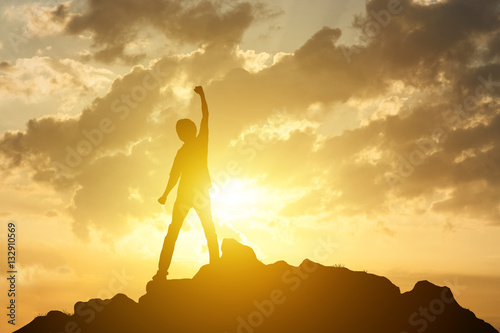Fotografiet Man on the peak of mountain and sunrise or sunset background lan