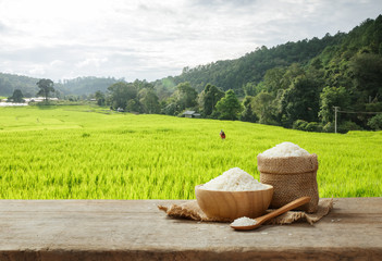 Jasmine Rice in bowl and burlap sack on wooden table with the ri