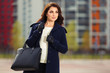 © Wrangler - Happy young fashion woman with handbag walking on city street