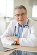 © goodluz - Portrait of senior doctor sitting in medical office