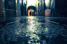 Focus On Wet Ground Along Dark Medieval Alley On A Rainy Night, Butter Slip, Kilkenny Ireland.