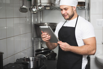 Wall Mural - Smiling chef reading on tablet