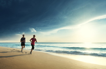 Wall Mural - Man and women running on tropical beach at sunset