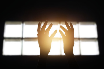 Wall Mural - Woman hands praying for blessing from god in building on dark bacground