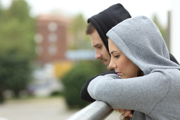 Wall Mural - Sad couple of teens looking down in a balcony