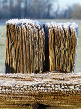 Weathered And Cracked Wooden Fence Post Covered In Frost On A Cold Sunny Winter's Morning