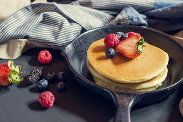 Home made pancakes with berries on metal frying pan decorated wi