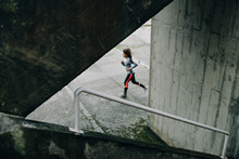 Sporty Woman Running On Winter Rainy Day. Urban Female Athlete Exercising On Asphalt.