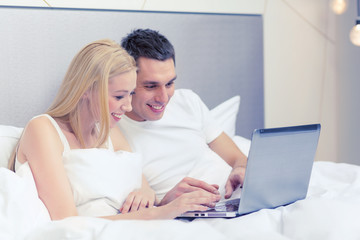 Poster - smiling couple in bed with laptop computer