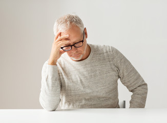 sad senior man sitting at table