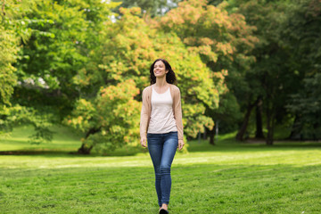 beautiful happy young woman walking in summer park