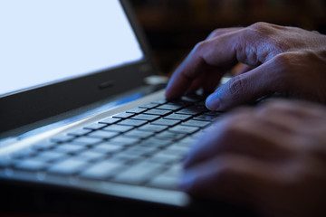 Selective focus on man two hand typing laptop/PC/computer keyboa