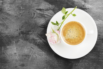 Espresso coffee in a white cup and a pink rose on a dark backgro