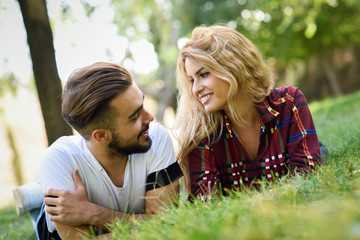 Wall Mural - Beautiful young couple laying on grass in an urban park.