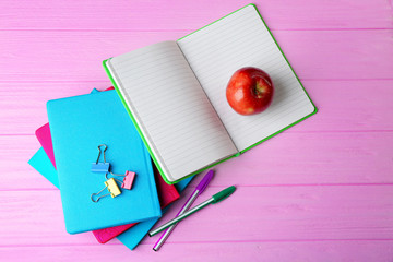 Wall Mural - Notebooks and apple on wooden background