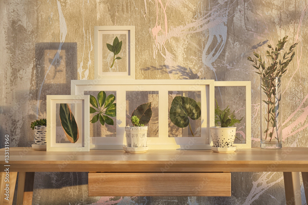 White frames with green leaves on wooden table