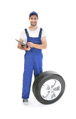 Wall Mural - Young mechanic in uniform with a clipboard on white background