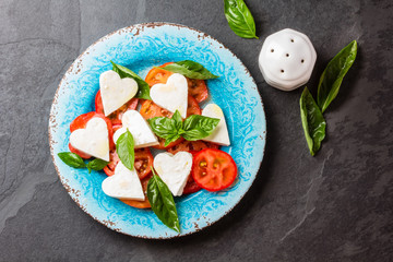 Caprese salad with tomatoes, cheese hearts, basil. Valentine day menu