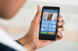 © Andrey Popov - Person Using Smart Home System On Mobilephone