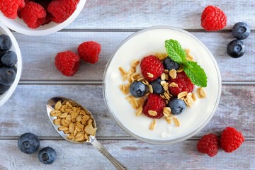 Wall Mural - greek yogurt with sweet berries and granola, overhead scene on rustic wood