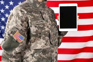 Wall Mural - Close up view of female soldier holding tablet computer, with USA flag on background