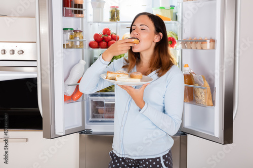 Cuadros en Lienzo Woman Eating Sweet Food Near Refrigerator