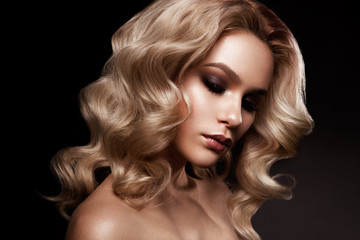 Close-up portrait of beautiful woman with bright make-up and hairstyle. Black background.