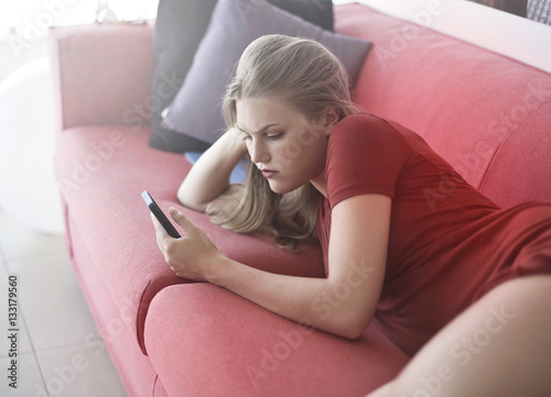 Blonde Girl Playing With Phone On Red Sofa Buy This Stock Photo And Explore Similar Images At Adobe Stock Adobe Stock