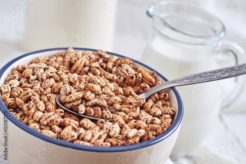Fotografia, Obraz Puffed barley cereal in bowl with pitcher of milk in background