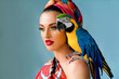 Portrait of young attractive woman in african style with ara parrot on her showlder on colorful background