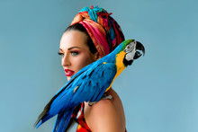 Portrait Of Young Attractive Woman In African Style With Ara Parrot On Her Showlder On Colorful Background