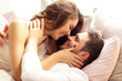 © Kalim - Young couple kissing in bed