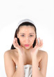 © sorocka - Young long-haired brunettein towel applies the cream to face on a white background