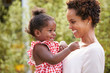 © Monkey Business - Young African American mother holds baby daughter in garden