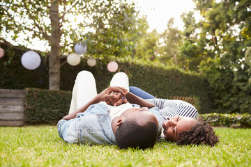 Wall Mural - Young black couple lying on grass looking at each other