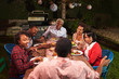 © Monkey Business - Adult black family talking at dinner in their garden