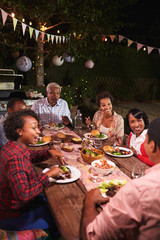 Wall Mural - Adult black family enjoy dinner together in garden, vertical