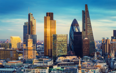 Poster - London, United Kingdom - The bank district of central London with famous skyscrapers in golden shine and other landmarks at sunset with blue sky