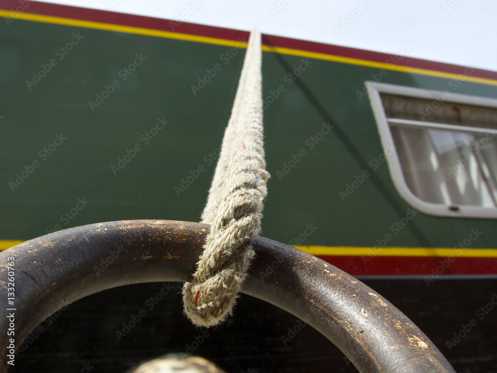 Canal boat mooring, rope attached to a rusted ring with boat in the ...