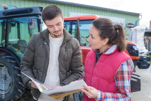 Foto saleswoman convincing young famrer to buy new agricultural machinery