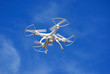 White unmanned drone quad copter flying in blue sky