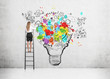 © ImageFlow - Rear view of a blond woman standing on a ladder and drawing a large and colorful light bulb sketch on a concrete wall.