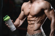 © antondotsenko - Handsome athletic fitness man holding a shaker and posing gym